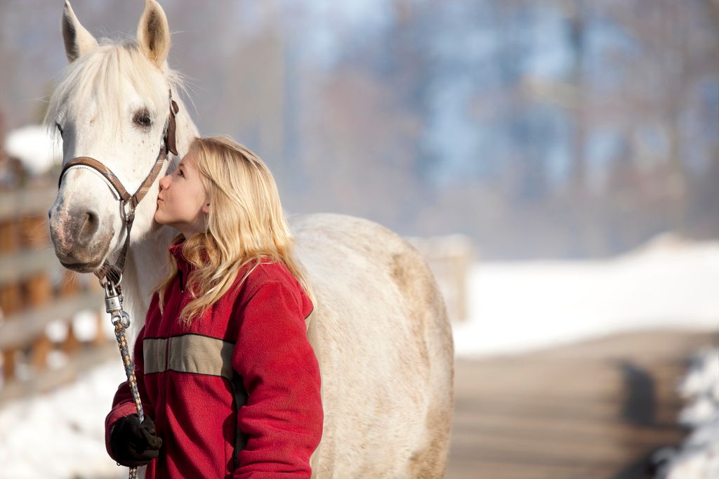 Pige kysser sin pony udenfor i sneen