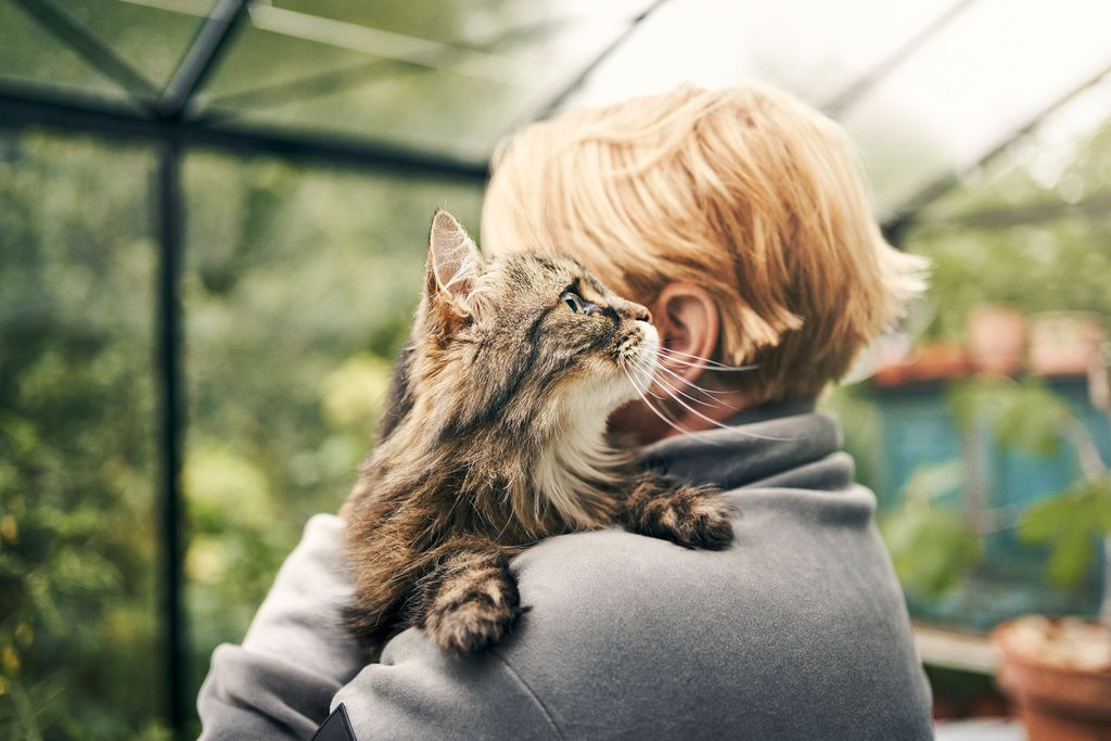 Kvinde står med sin kat i favnen