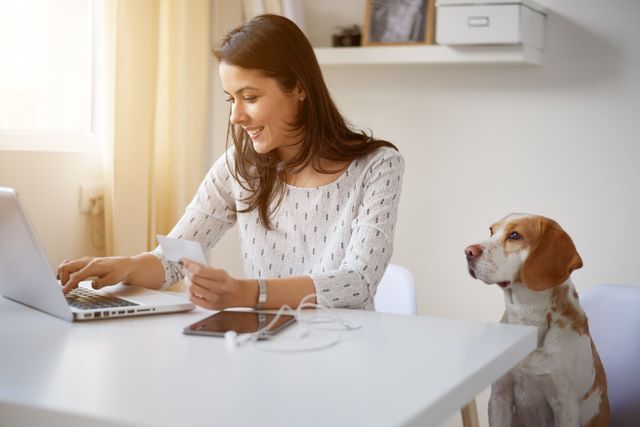 Kvinde med computer sidder med en hund ved siden af.
