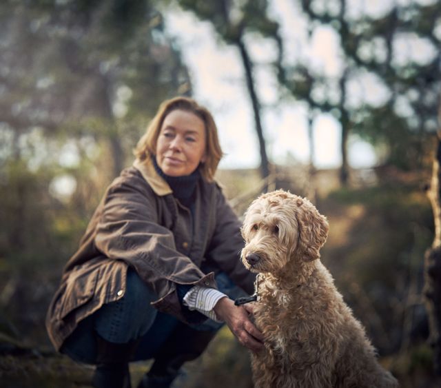 En kvinde sidder ude med sin hund i naturen
