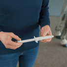 Dyrlæge står med ormekur i håndenavmaskar en häst.