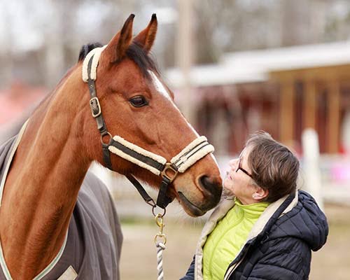 Kvinde med hest udendørs.